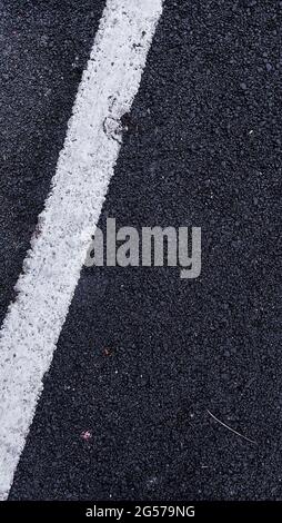 Vertikale Nahaufnahme der weiß gestrichenen Linien auf einer asphaltierten Straße Stockfoto