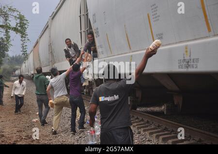 Menschen werfen Essen an Mittelamerikaner, die im Zug vorbeifahren, den sie La Bestia nennen. Stockfoto