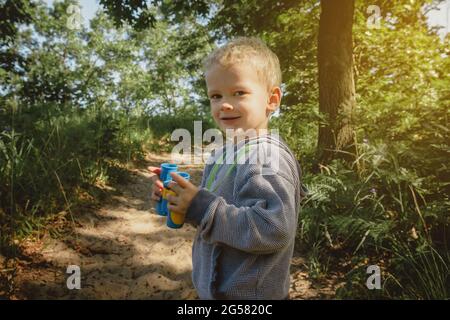 Kleiner Junge, der im Indiana Dunes State Park wandern und Vögel beobachten kann, auf einem Weg mit dem Fernglas. Stockfoto