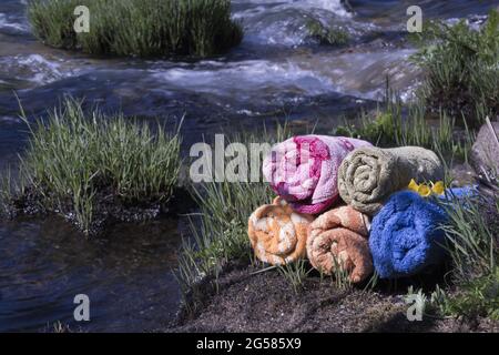 Stapel von bunten Handtüchern Seifen in der Nähe eines Flusses Stockfoto