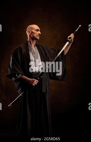 Ansicht eines blinden und kahlen Mannes, der einen Kimono trägt und ein Katana in den Händen hält Stockfoto