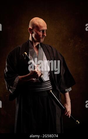 Ansicht eines blinden und kahlen Mannes, der einen Kimono trägt und ein Katana in den Händen hält Stockfoto