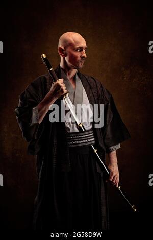 Ansicht eines blinden und kahlen Mannes, der einen Kimono trägt und ein Katana in den Händen hält Stockfoto