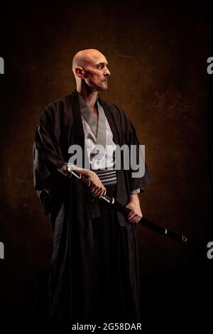 Ansicht eines blinden und kahlen Mannes, der einen Kimono trägt und ein Katana in den Händen hält Stockfoto