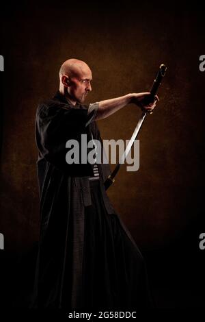 Ansicht eines blinden und kahlen Mannes, der einen Kimono trägt und ein Katana in den Händen hält Stockfoto