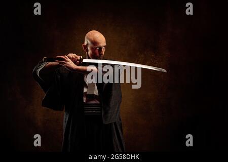 Ansicht eines blinden und kahlen Mannes, der einen Kimono trägt und ein Katana in den Händen hält Stockfoto