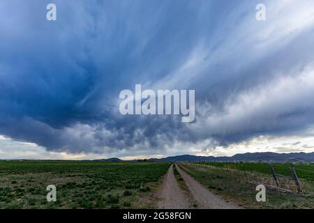 USA, Idaho, Bellevue, stürmischer Himmel über der Farmstraße in der Nähe von Sun Valley Stockfoto