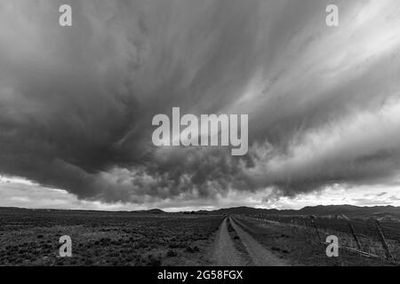 USA, Idaho, Bellevue, stürmischer Himmel über der Farmstraße in der Nähe von Sun Valley Stockfoto