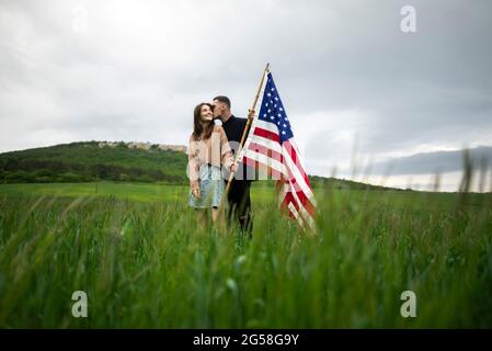 Junges Paar mit amerikanischer Flagge küssen in Weizenfeld Stockfoto