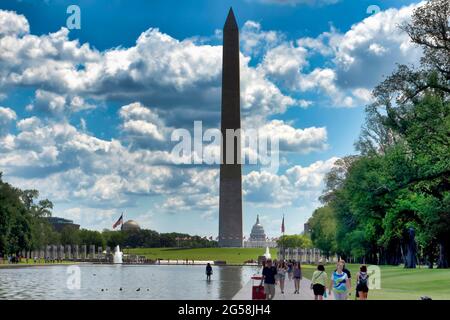 Besucher spazieren entlang des reflektierenden Pools in Washington D.C., mit dem Denkmal des Zweiten Weltkriegs und dem Kapitolgebäude im Hintergrund Stockfoto