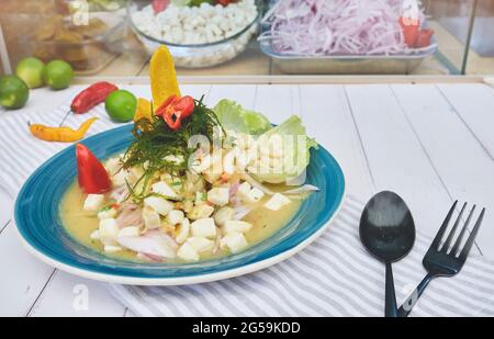 Peruanische Küche: Fisch Ceviche de Pota mit gebratenem Maniok, süßem Mais und Süßkartoffeln, serviert auf einem blauen Teller Stockfoto