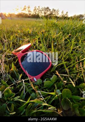 Vertikale Aufnahme von roten Sonnenbrillen auf dem Gras Stockfoto