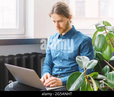 Fokussierter junger Mann in formeller Kleidung, der im Büro am Laptop arbeitet Stockfoto