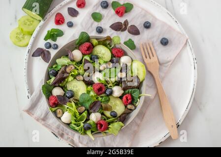 Frischer Sommersalat mit Rucola, Mozzarella, Kräutern und Beeren Stockfoto