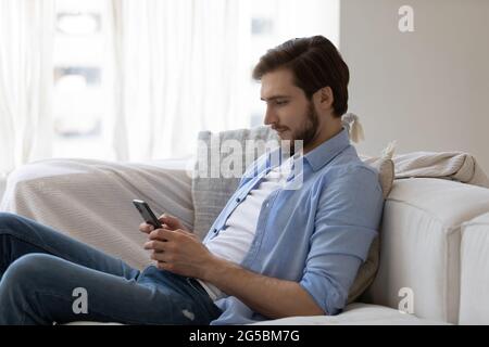 Fokussierter engagierter junger Mann mit Mobiltelefon Stockfoto