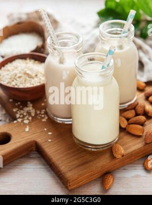 Alternative Arten von veganen Milchsorten in Glasflaschen auf betontem Hintergrund. Draufsicht Stockfoto