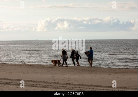 Stegna, Polen - 4. September 2020: Die Familie läuft mit ihrem Hund am Strand entlang Stockfoto