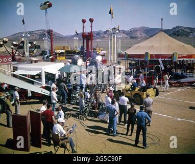 BARBARA STANWYCK JOAN FREEMAN und ELVIS PRESLEY am Drehort des Karnevals mit Movie Crew während der Dreharbeiten zu ROUSTABOUT 1964 Regisseur JOHN RICH Drehbuch Anthony Lawrence und Allan Weiss Kinematographie Lucien Ballard Kostümdesign Edith Head Wallis-Hazen / Paramount Picturms Stockfoto