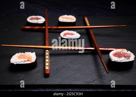 Drei in einer Reihe mit Sushi und Essstäbchen. Köstliches japanisches Essen. Orientalisches Speisekonzept Stockfoto