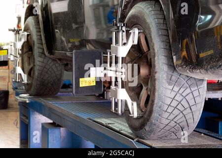 Autoreifen, die mit dem Aligner gespannt sind, werden in der Reparaturwerkstatt in der Garage einer automatischen Einstellung des Radwinkels, der Ausrichtung und der Radwaage unterzogen. Stockfoto