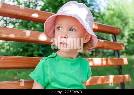 Kleines Mädchen in einem grünen T-Shirt und einem rosa panama spaziert im Sommer im Park Stockfoto