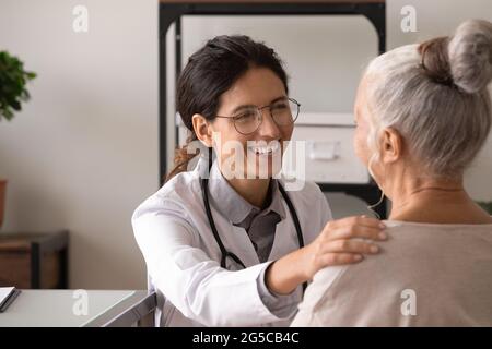 Lächelnder Arzt unterstützt die alte Patientin in der Klinik Stockfoto