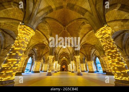 Weihnachtsdekorationslichter, die um Steinsäulen in den alten Kreuzgängen der Glasgow University, Glasgow, Schottland, Großbritannien, gewickelt sind Stockfoto