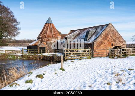 Historische Preston Mühle an einem bitterkalten sonnigen Tag im Schnee in East Linton, East Lothian, Schottland, Großbritannien Stockfoto