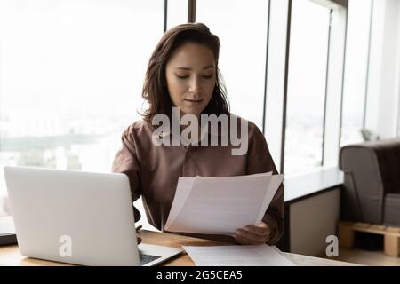 Konzentrierte junge Geschäftsfrau, die den Finanzbericht analysiert. Stockfoto