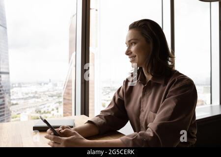 Verträumte glückliche junge Geschäftsfrau, die in der Ferne schaut. Stockfoto