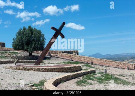 Riesige Eisenschwert im Boden stecken, um die Zeit mit dem Schatten (Sonnenuhr) in der mittelalterlichen Burg von Lorca, Murcia, Spanien zu sagen. Und mit einem Ventilator Stockfoto