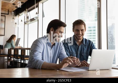 Glückliche aufrichtige freundliche junge männliche Kollegen lachen, genießen Pause Zeit. Stockfoto