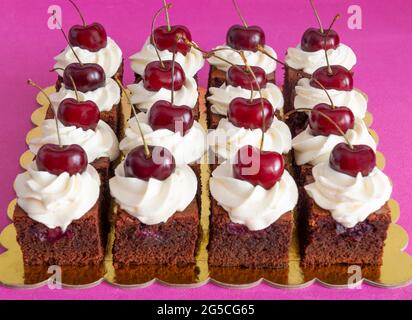 Brownie-Würfel mit Kirschen und weißer Creme Stockfoto