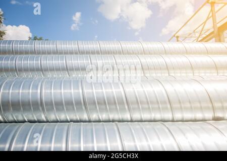 Lüftungsrohre gegen den blauen Himmel. Stahlrohre, Teile für den Bau von Luftkanälen für eine industrielle Klimaanlage in einem Lager Stockfoto