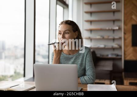 Lächelnd Attraktive Millennial-Frau, die auf dem Smartphone Audio-Nachrichten aufzeichnet. Stockfoto