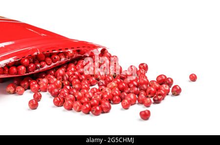 Rosa Pfefferkörner - getrocknete Früchte von peruanischem peppertree ( Schinus molle ), mit roter Plastikverpackung in der Nähe, Nahaufnahme Detail, weißer Hintergrund Stockfoto