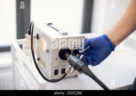 Endoskopie im Krankenhaus. Nahaufnahme eines modernen gastroduodenoskopischen Geräts und der Hand eines nicht erkennbaren Arztes in einem sterilen blauen Gummihandschuh, der sich auf das Endoskopieverfahren vorbereitet Stockfoto