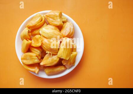 Draufsicht auf die Scheibe der Jackfruits in einer Schüssel auf orangefarbenem Hintergrund. Stockfoto