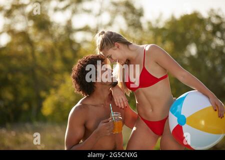 Junge multiethnische Paare schauen sich in Badeanzügen eng in der Natur an Stockfoto