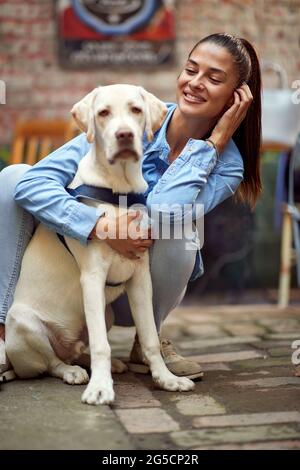 Porträt einer schönen jungen Frau, die ihren Hund umarmt und lächelt Stockfoto