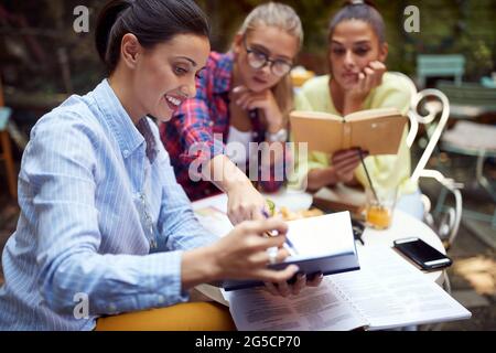 Drei junge Erwachsene kaukasische Frauen studieren gemeinsam im Café im Freien. Stockfoto