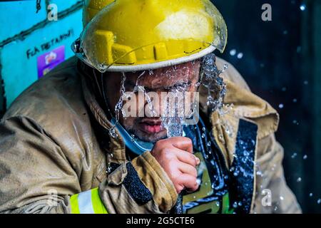 Quezon City. Juni 2021. Ein Feuerwehrmann nutzt eine Wasserleitung, um sich während einer Feuermission in einem Wohngebiet in Quezon City, Philippinen, am 26. Juni 2021 abzukühlen. Quelle: Rouelle Umali/Xinhua/Alamy Live News Stockfoto