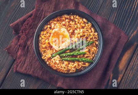Schüssel Ramen mit weich gekochtem Ei und Spargel auf dem Holztisch Stockfoto