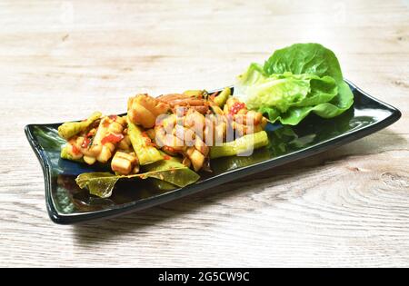 Würzig gebratener Tintenfisch mit Chili und Zitronenblatt-Salat auf dem Teller Stockfoto