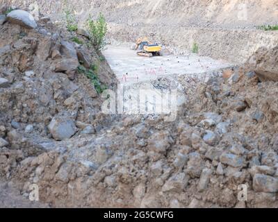 Der Gleislader wird in Tagebaugruben mit Steinen beworfen. Schwere Maschinen im Tagebau, Bagger, Planierraupen und Lastwagen. Graben und Aushub o Stockfoto