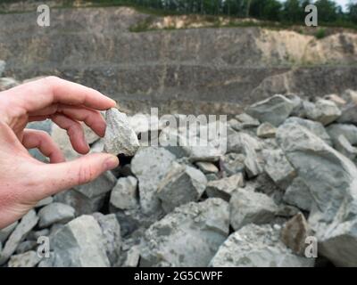 Hand halten Stein oder Nugget im offenen Steinbruch. Der Experte fand den Ort der Mineralquelle Stockfoto