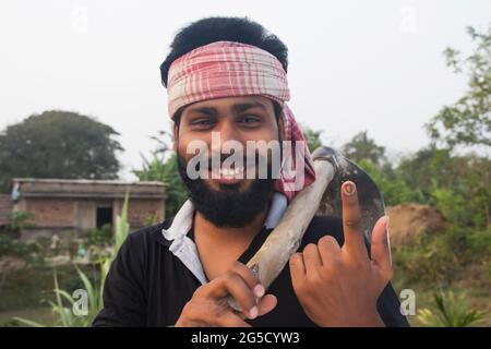 Porträt eines jungen erwachsenen Bauern mit einer Schaufel mit Wählermarkierung am Finger auf dem landwirtschaftlichen Feld Stockfoto