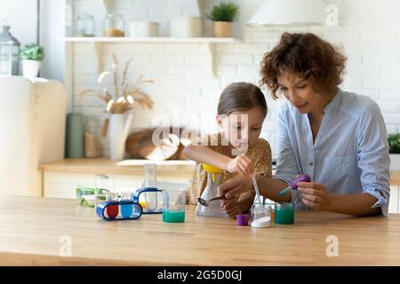 Konzentriertes kleines Kind, das zu Hause Experimente mit Mama macht. Stockfoto