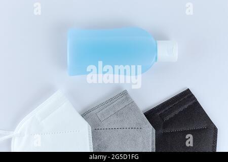 Antibakterielles Alkoholdesinfektionsmittel und schwarze, graue FFP2- oder N95-Gesichtsmasken. Auf weißem Hintergrund. Flache Schicht aus der Draufsicht. Schutz vor Kov Stockfoto