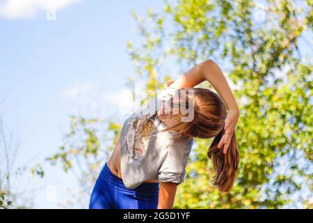 Defocus caucasian preteen Mädchen tun körperliche Bewegung im Park, Wald, im Freien, draußen. Meditation, Konzentration. Gesunder Lebensstil. Seitenbiegung Stockfoto